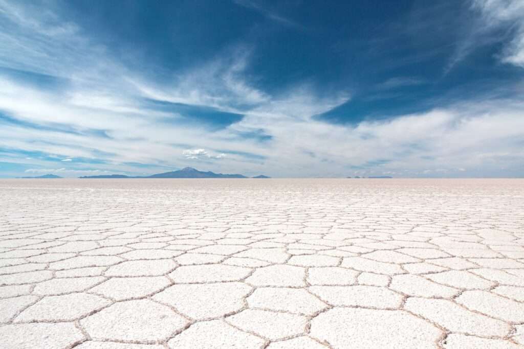 Salt flat desert landscape with cracked dry soil under blue sky and white clouds